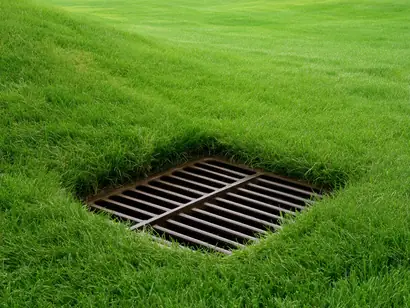 Cast iron catch basin grate installed flush in a residential lawn in the GTA
